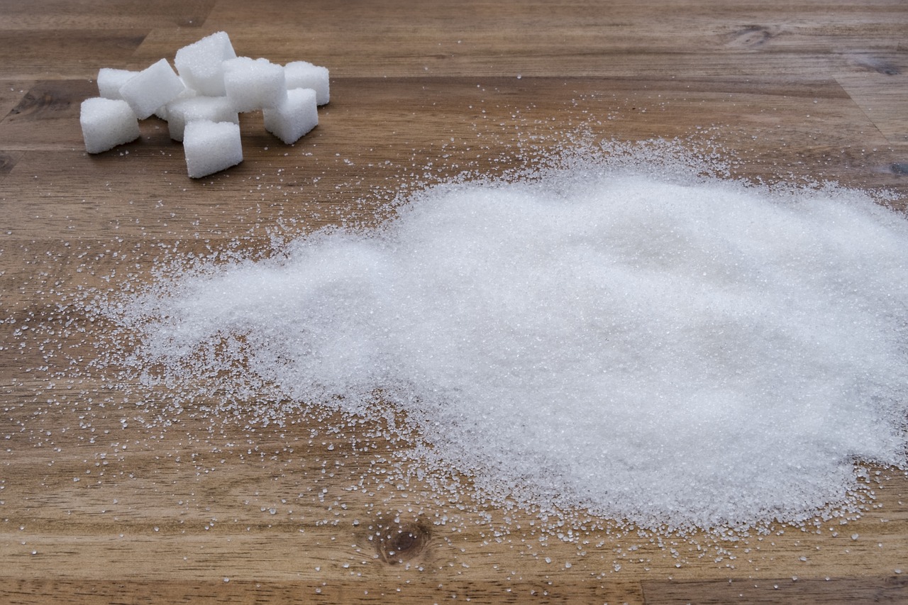 A few sugar cubes on a wooden table and a pile of regular sugar, is it good for your health?